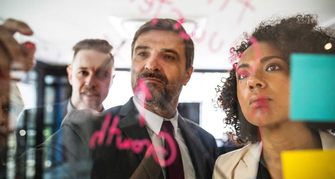 Three people solving problems on a whiteboard.