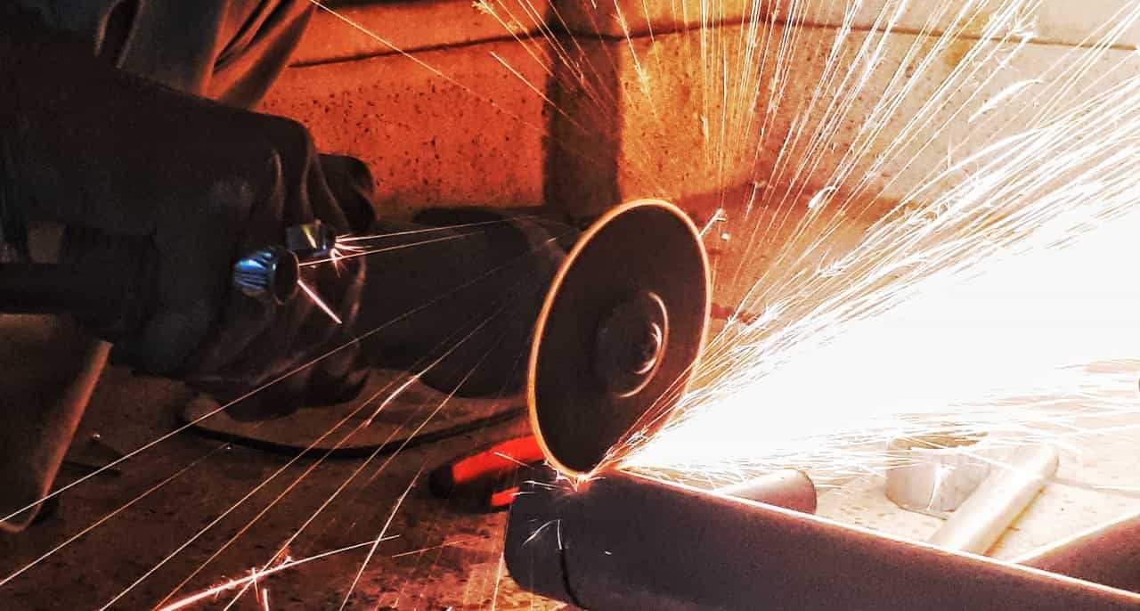 Sparks flying off a grinder being used to cut through a pipe.